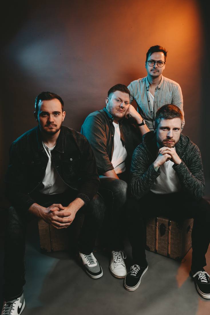Band photo of Feed Them Hope: four musicians in a studio with orange lighting